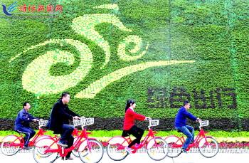 市民骑公共自行车路过市人民广场一处花坛。记者 张驰